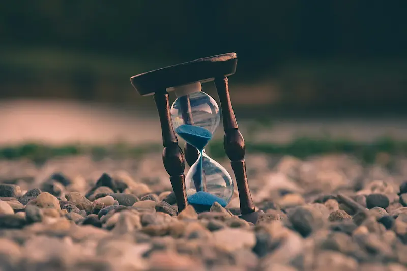 Compra tiempo, un reloj de area en la tierra rodeado de piedras