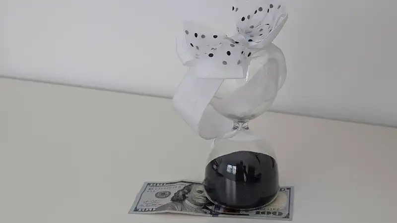 ¿Cuánto ahorrar cada mes? El error que todos cometen (y la respuesta real) ahorrar cada mes, reloj de arena sobre billete de 100 dolares