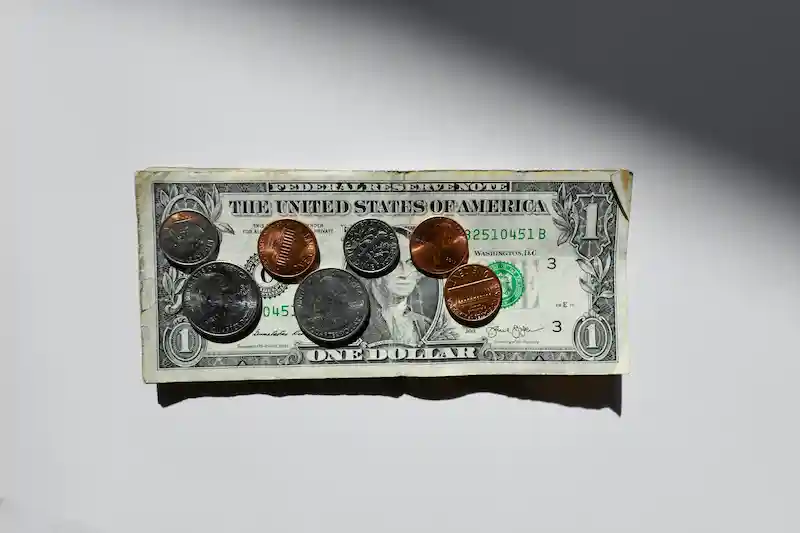 Guía cómo administrar el dinero y hacerlo fácil by Daury DiCaprio dinero en dolares y monedas, las monedas sobre un billete de un dolar