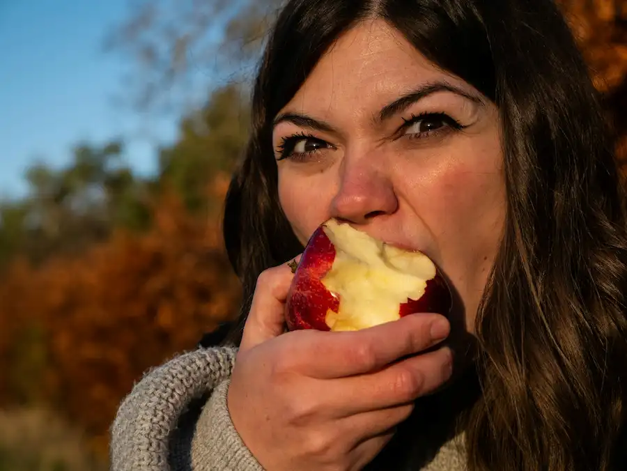 Cómo comer saludable puede hacerte más rico (literalmente) comer saludable te ahorra dinero, mujer come manzana