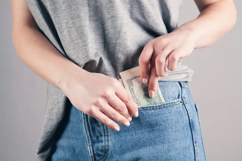 mujer guarda dinero en bolsillo de su derecha, pantalo jeans, no se ve la cara