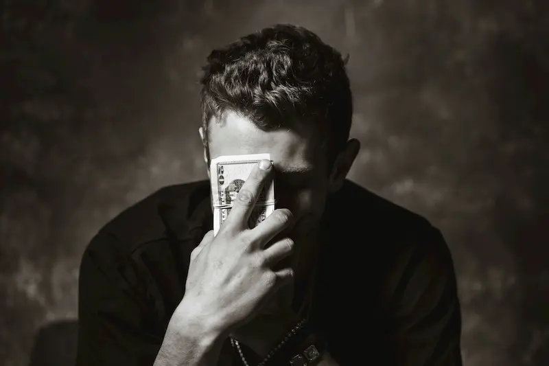 hombre con dinero en frente a la cara probleas y mitos sobre el dinero